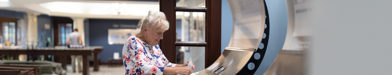 Senior woman in Thomaston Savings Bank branch using a coin processing machine in lobby