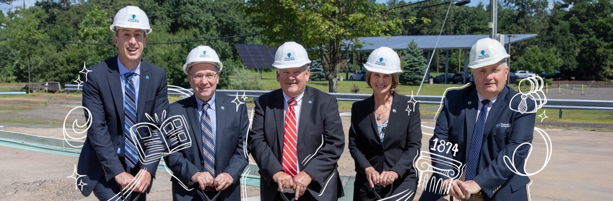 Thomaston Savings Bank executives wearing hardhats and holding shovels at a dig site.