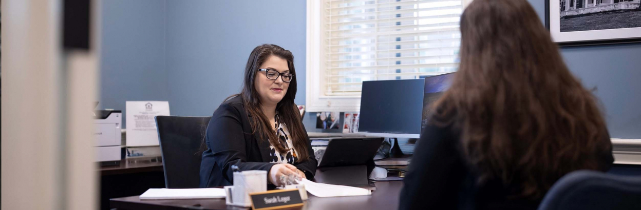 A Thomaston Savings Bank employee working with a customer and doing paperwork at desk