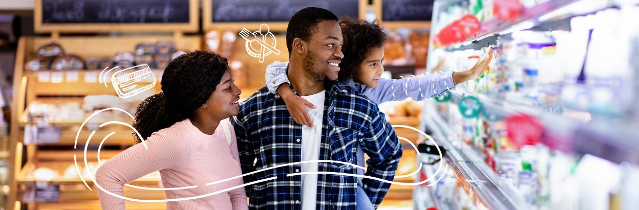 A couple with their child grocery shopping together in store, while child reaches towards an item