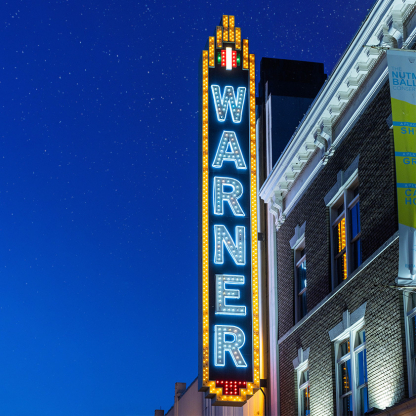 Night time shot of lit up Warner Theater marquee 