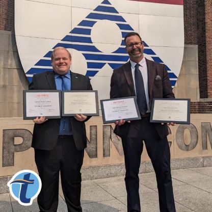 Patrick Quinn and Todd Burton hold diplomas from the American Bankers Association Stonier Graduate School of Banking in front of a University of Pennsylvania sign.