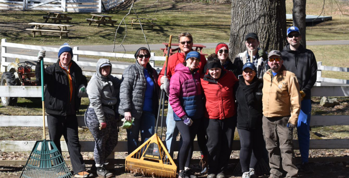 A group of Thomaston Savings Bank employees doing a volunteer project outdoors, wearing winter jackets and holding rakes