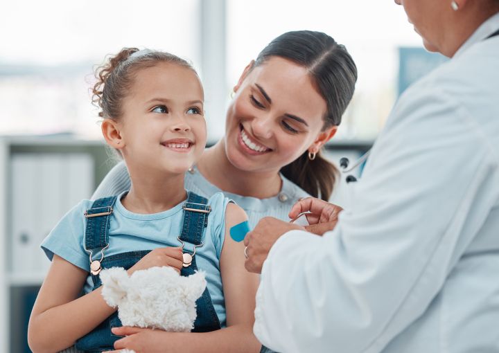 mother holding child on lap while doctor applies a bandaid