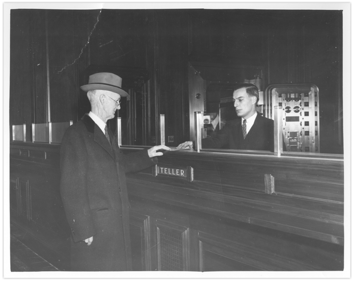 A historical Thomaston Savings Bank black and white photograph of a bank teller and a customer making a deposit